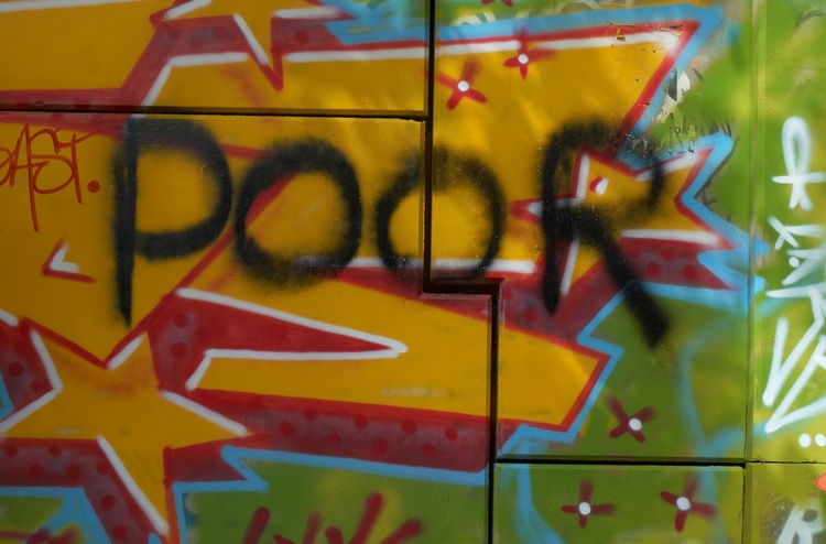 The word 'poor' sprayed over other graffiti