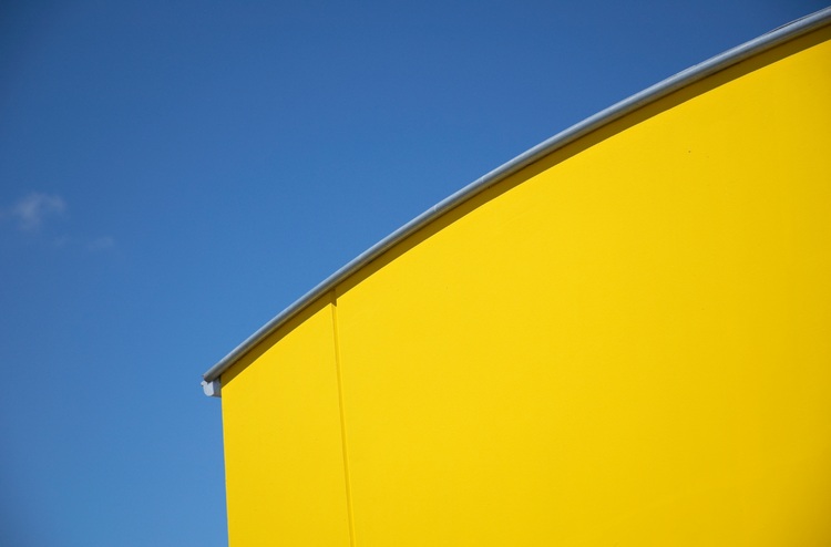 A large yellow wall against a bright blue sky