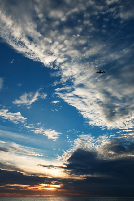 An aircraft silhouetted against clouds and sunset