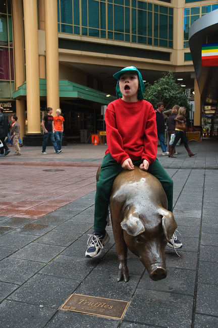 Michael sitting on a bronze pig sculpture in Rundle Mall