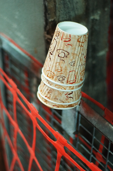Paper coffee cups hanging from the top of a piece of metal on a construction site