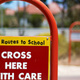 Sign reading 'safe routes to school', 'cross here with care'