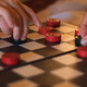 Hands moving pieces on a draughts board