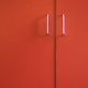 A pair of cupboard door handles on orange doors